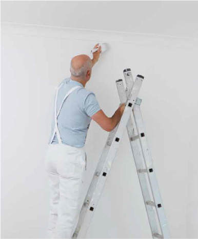 Employee painting a wall on a ladder